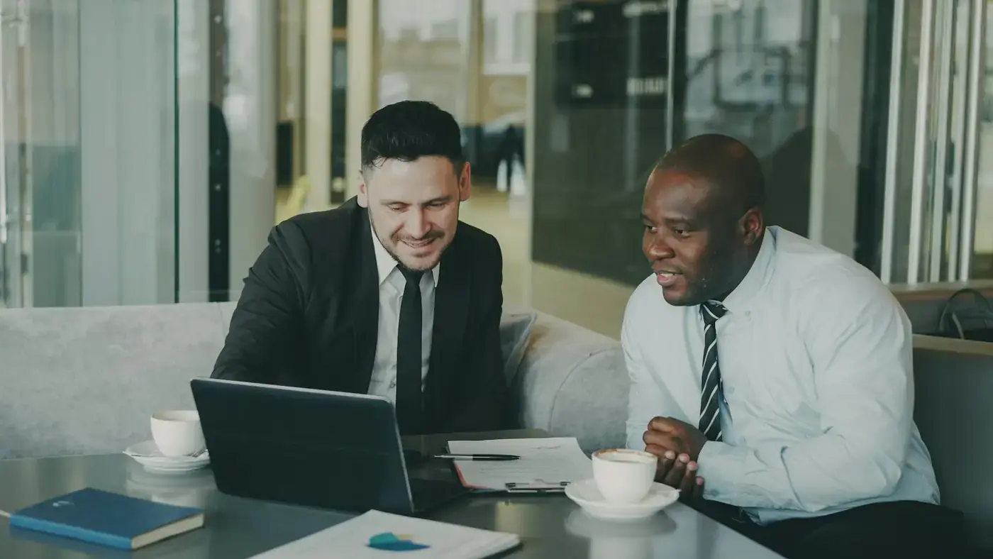 Two executives reviewing terms over a laptop